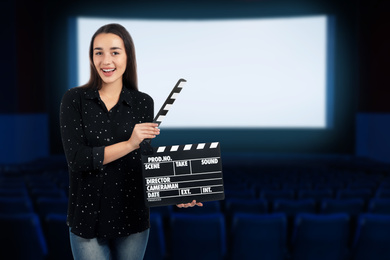 Image of Young woman with clapperboard in cinema, space for text