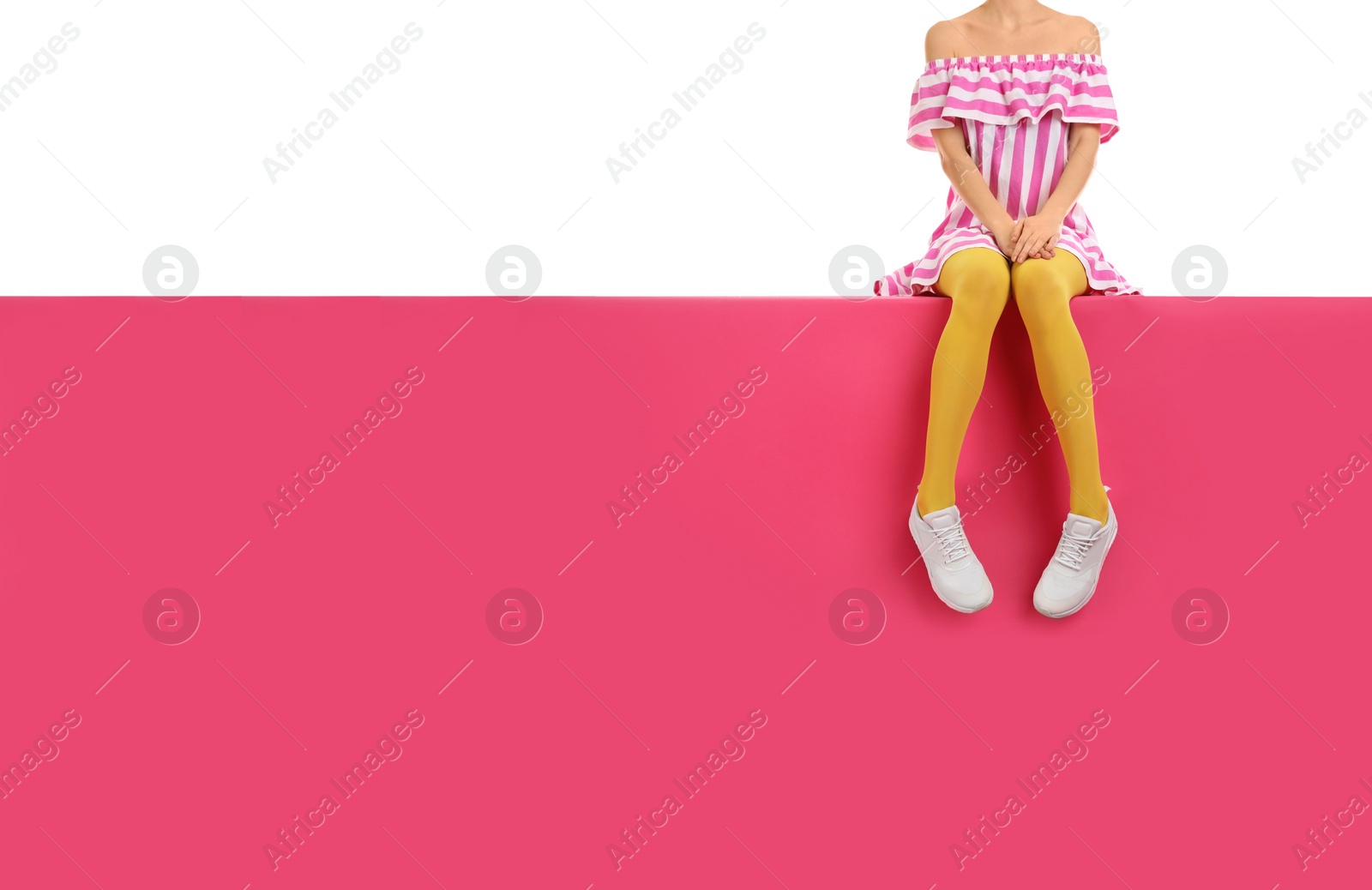 Photo of Woman wearing yellow tights and stylish shoes sitting on color background, closeup