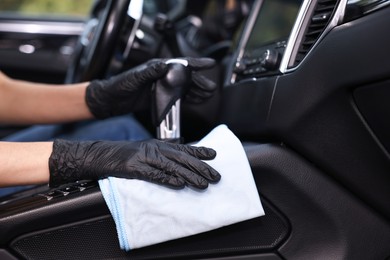 Woman wiping her modern car with rag, closeup