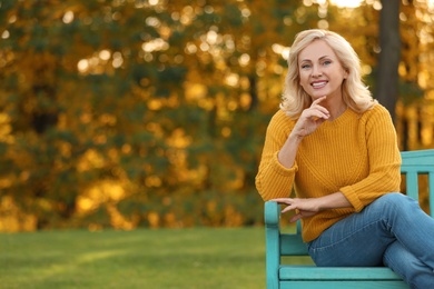 Portrait of happy mature woman on bench in park
