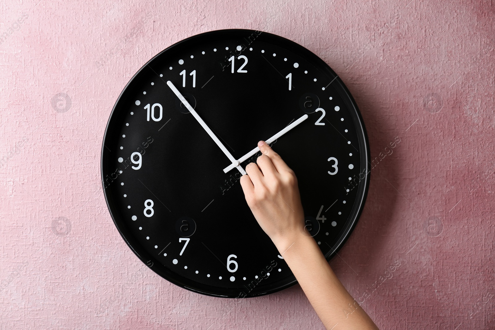 Photo of Woman changing time on big wall clock
