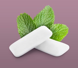 Menthol chewing gum pillows and mint leaves on dusty pink background