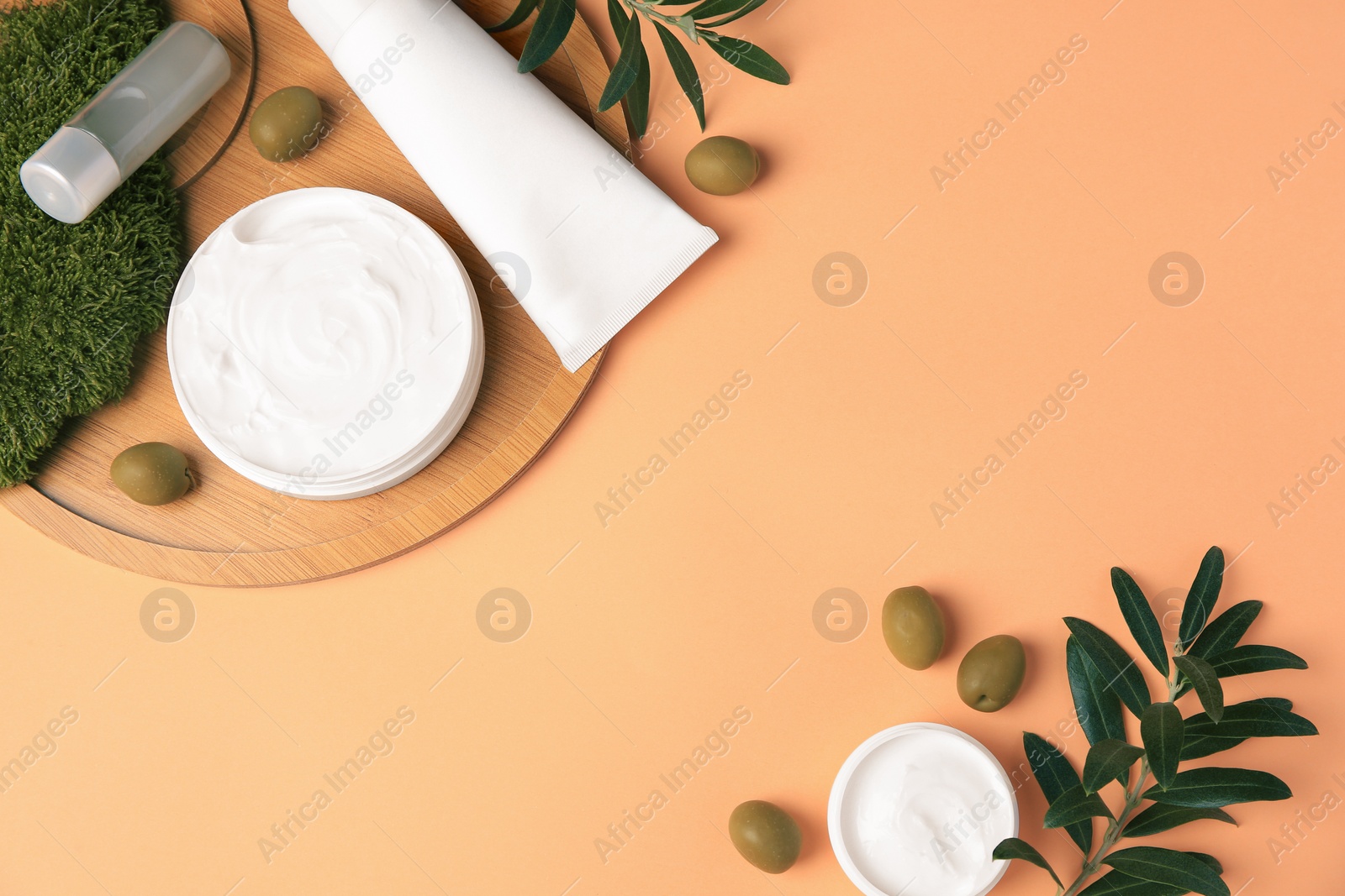 Photo of Flat lay composition with different cosmetic products and olives on pale orange background. Space for text