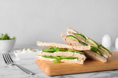 Photo of Wooden board with traditional English cucumber sandwiches on table. Space for text