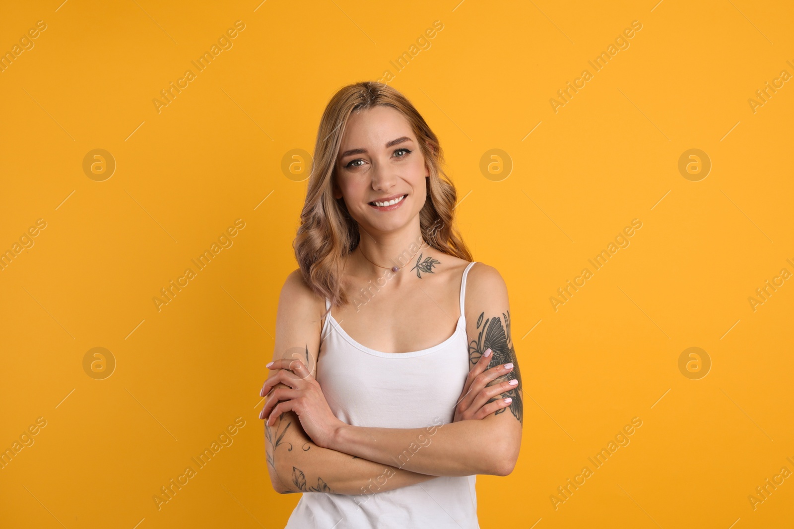 Photo of Beautiful woman with tattoos on body against yellow background