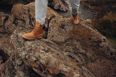 Photo of Man wearing stylish hiking boots on steep cliff, closeup