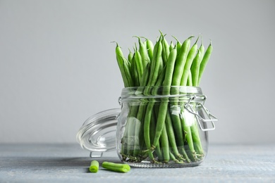 Photo of Fresh green beans in glass jar on grey wooden table
