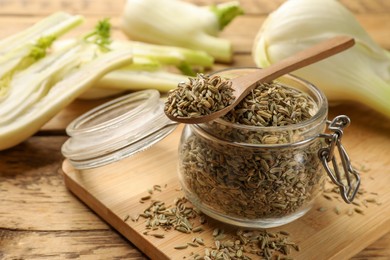 Photo of Jar and spoon with fennel seeds on wooden table, closeup