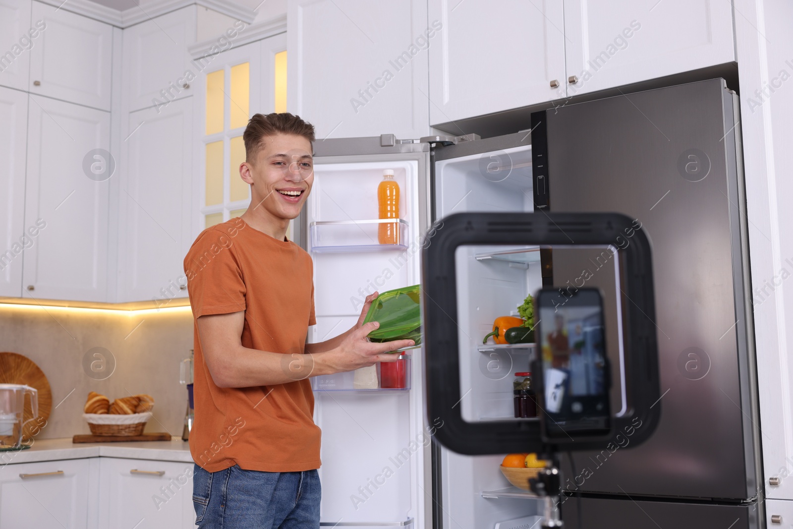 Photo of Smiling food blogger explaining something while recording video in kitchen