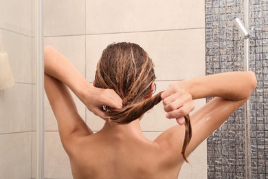 Young woman washing hair in shower at home