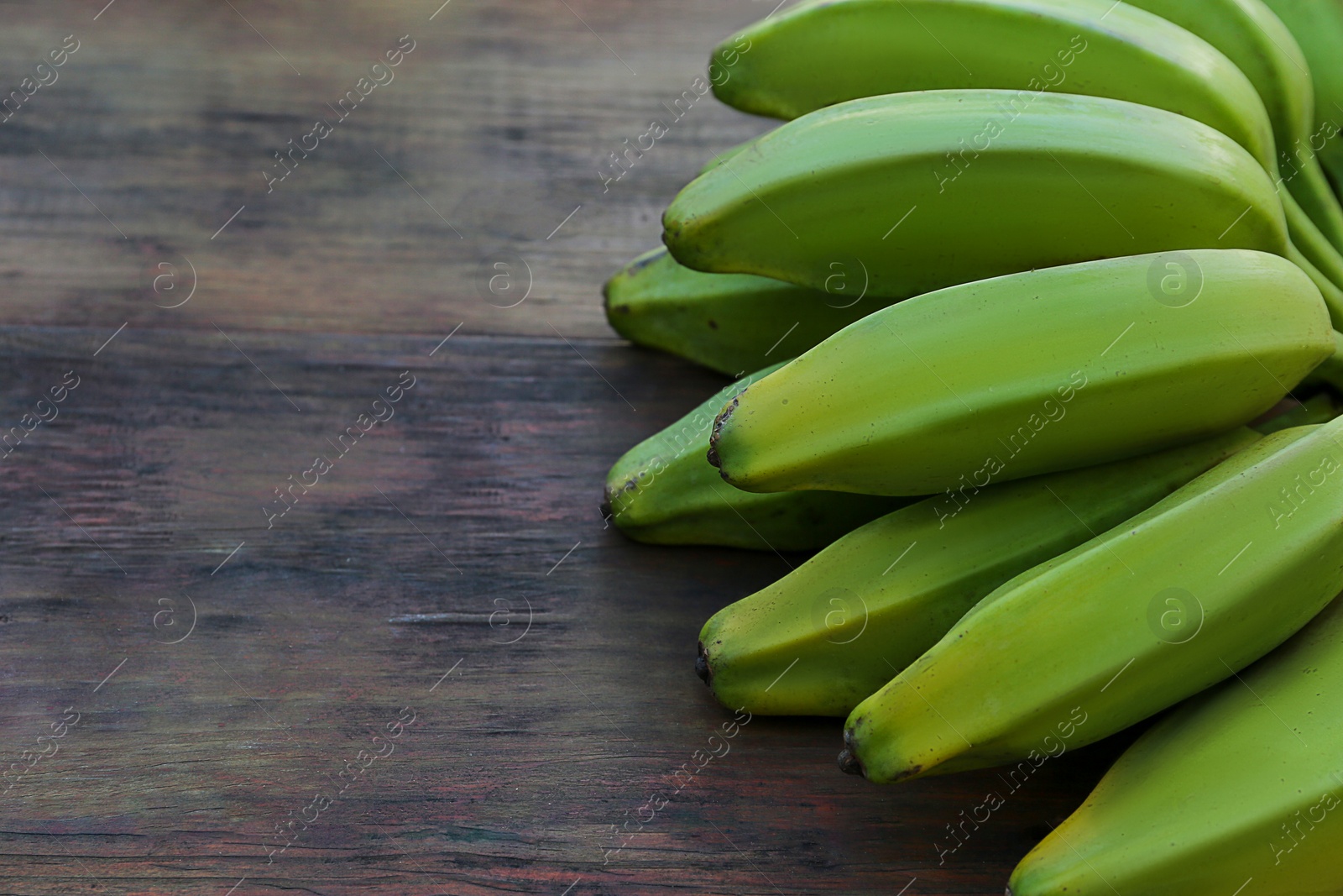 Photo of Bunch of delicious bananas on wooden table, closeup. Space for text