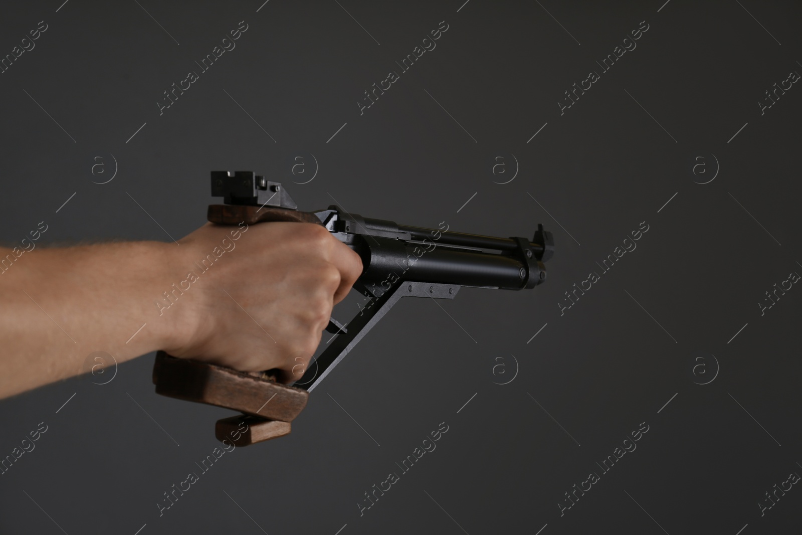 Photo of Gun shooting sport. Man aiming standard pistol on dark background, closeup