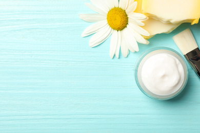 Photo of Jar of cream, soap, brush and chamomile on light blue wooden table, flat lay. Space for text