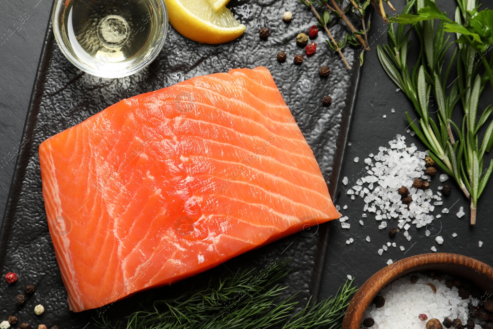 Photo of Fresh raw salmon and ingredients for marinade on black table, flat lay