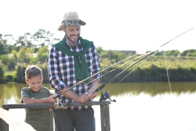 Father and son fishing together on sunny day