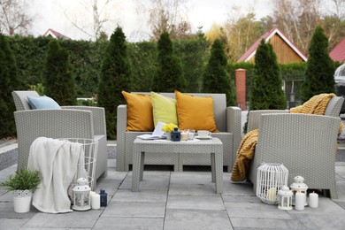 Photo of Beautiful rattan garden furniture, soft pillows and different decor elements in backyard