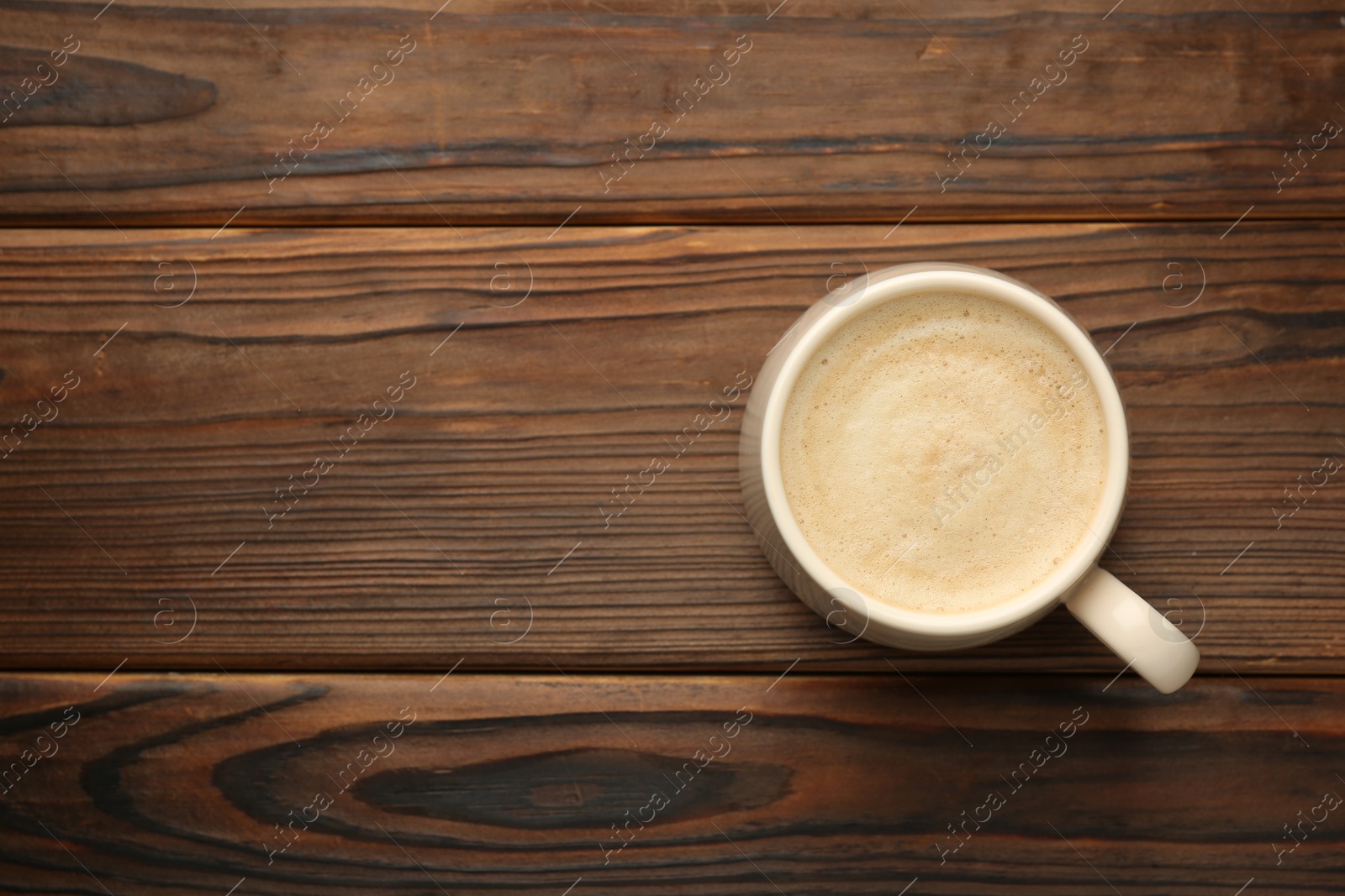 Photo of Cup of coffee on wooden table, top view. Space for text