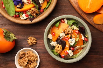 Photo of Delicious persimmon salad with cheese and pomegranate served on wooden table, flat lay