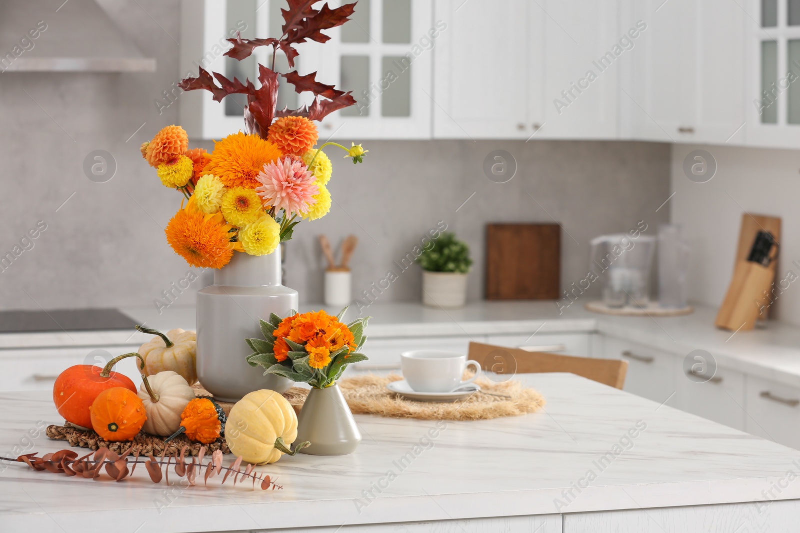 Photo of Beautiful autumn bouquets and pumpkins on marble table in kitchen