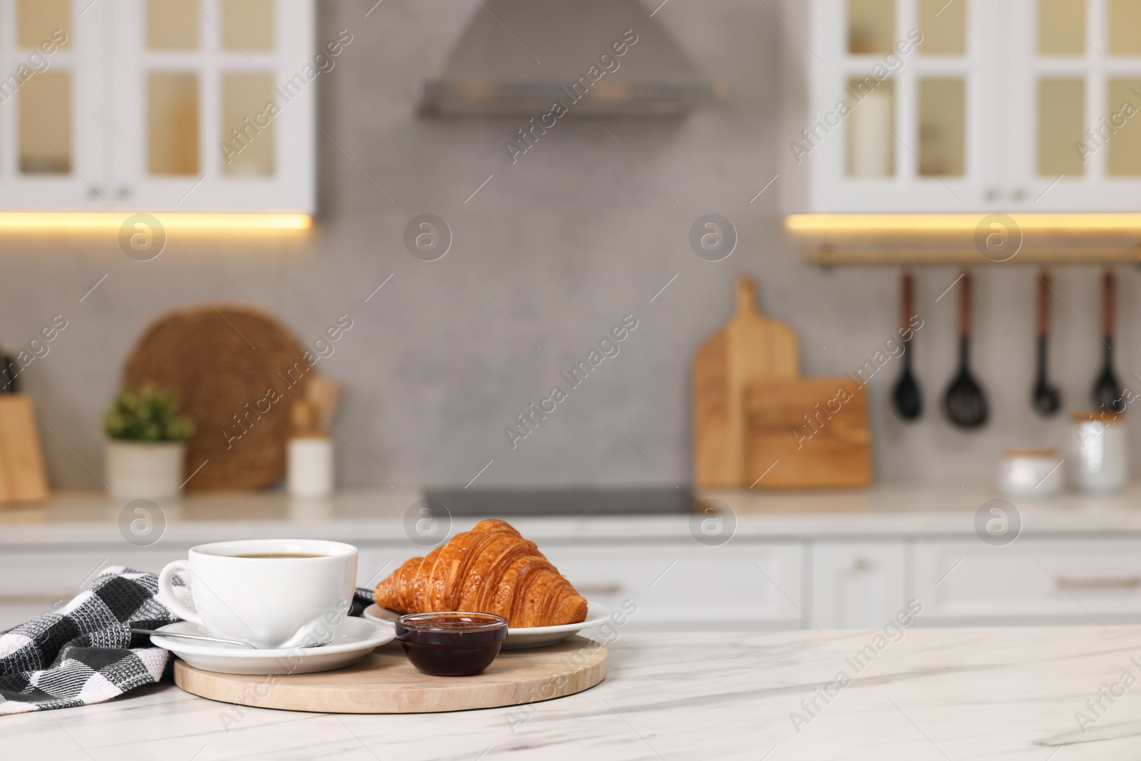 Photo of Breakfast served in kitchen. Fresh croissant, coffee, and jam on white table. Space for text