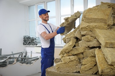 Photo of Construction worker with used glass wool in room prepared for renovation