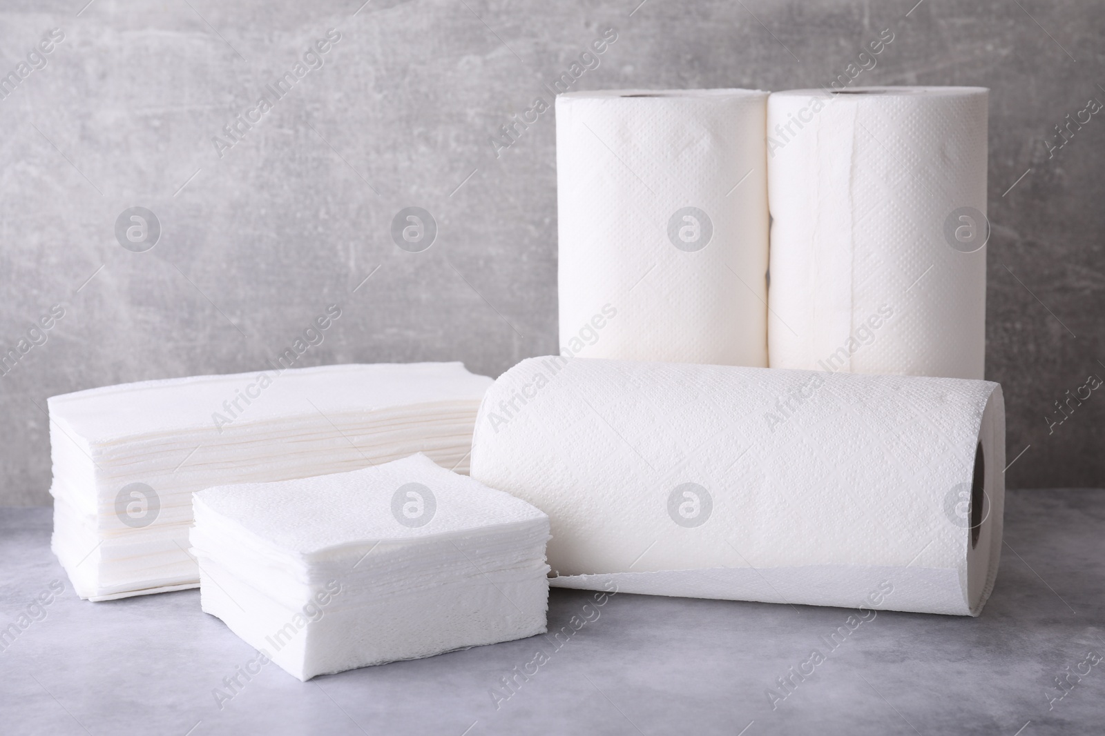 Photo of Rolls and stacks of paper towels on grey table