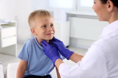 Photo of Endocrinologist examining boy's thyroid gland at hospital, closeup