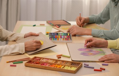 Artists drawing with soft pastels and pencils at table indoors, closeup