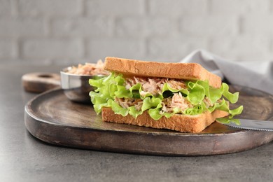 Delicious sandwich with tuna, lettuce leaves and cucumber on light grey table