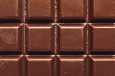 Tasty milk chocolate bar as background, top view
