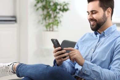 Photo of Handsome young man using smartphone in office