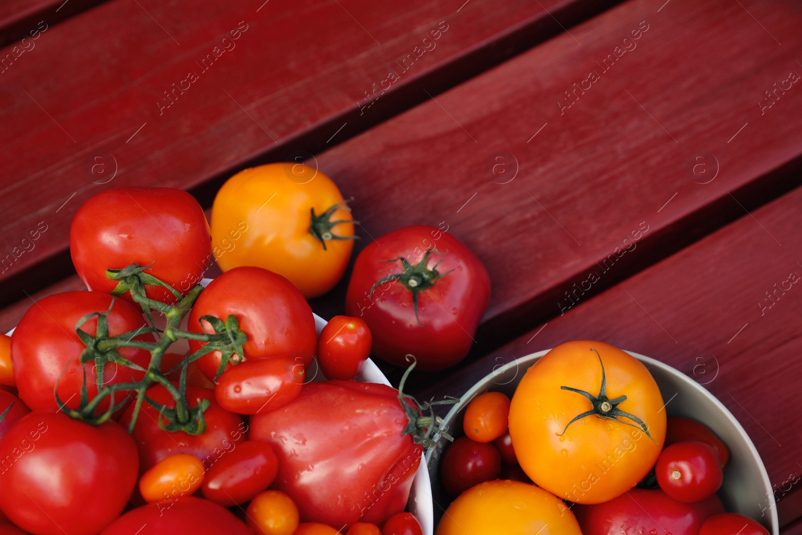 Photo of Bowls with fresh tomatoes on wooden table, flat lay. Space for text