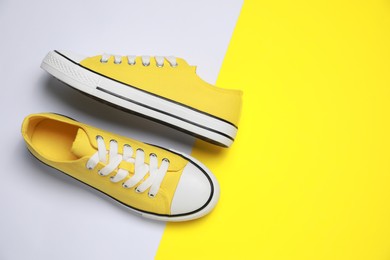 Photo of Pair of yellow classic old school sneakers on color background, flat lay. Space for text