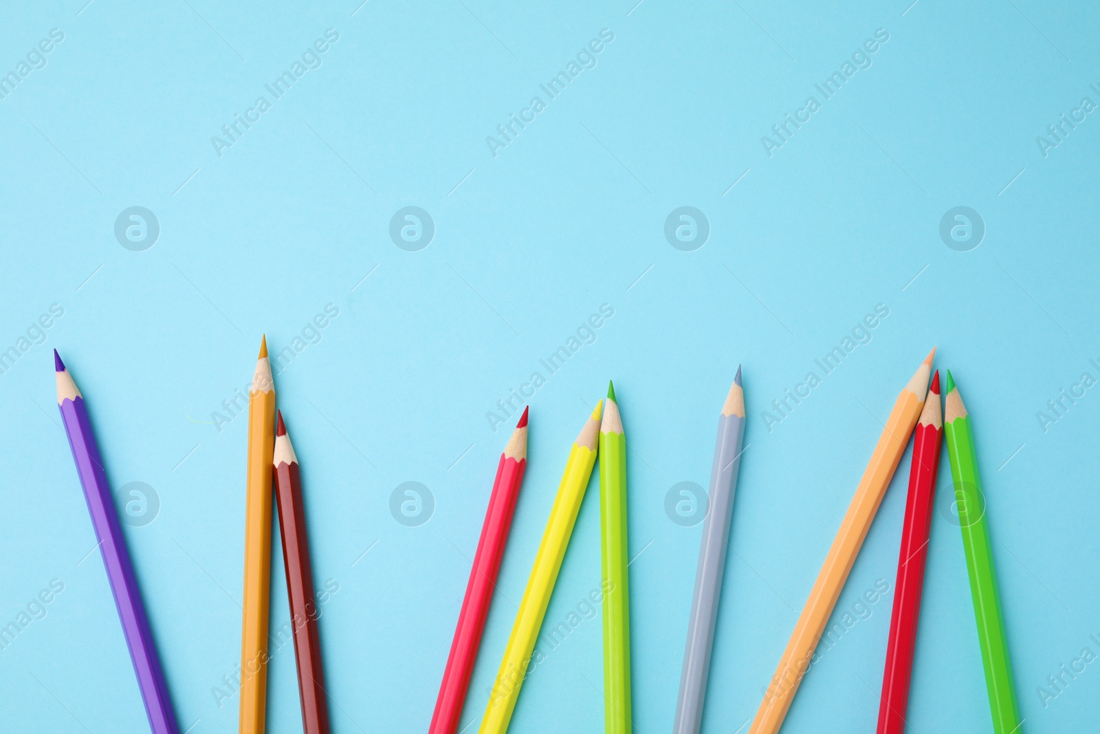 Photo of Colorful wooden pencils on light blue background, flat lay. Space for text