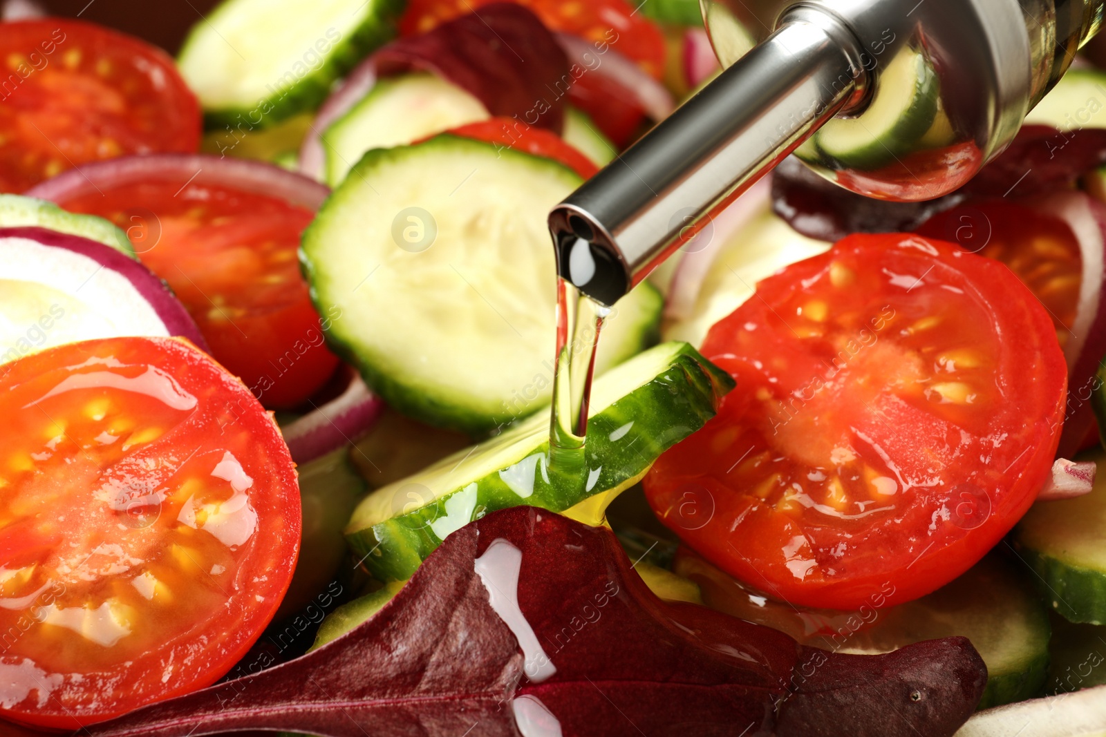 Photo of Adding cooking oil to delicious salad, closeup