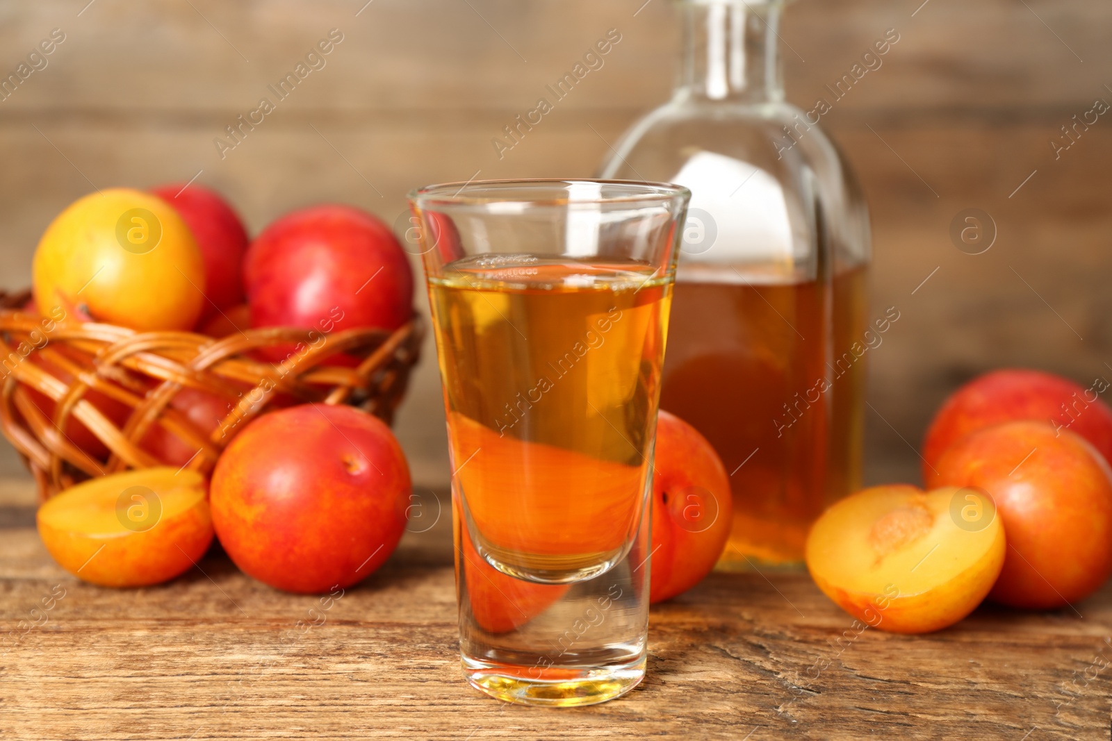 Photo of Delicious plum liquor and ripe fruits on wooden table. Homemade strong alcoholic beverage