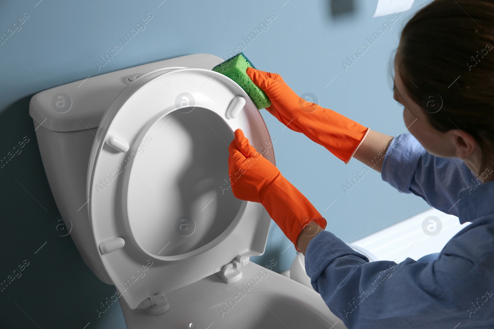 Photo of Woman cleaning toilet bowl in bathroom