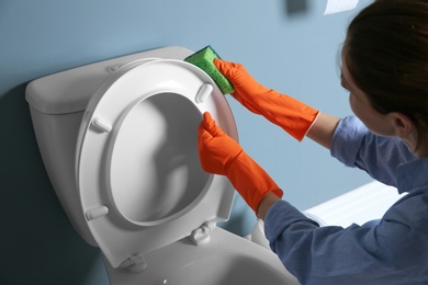 Woman cleaning toilet bowl in bathroom