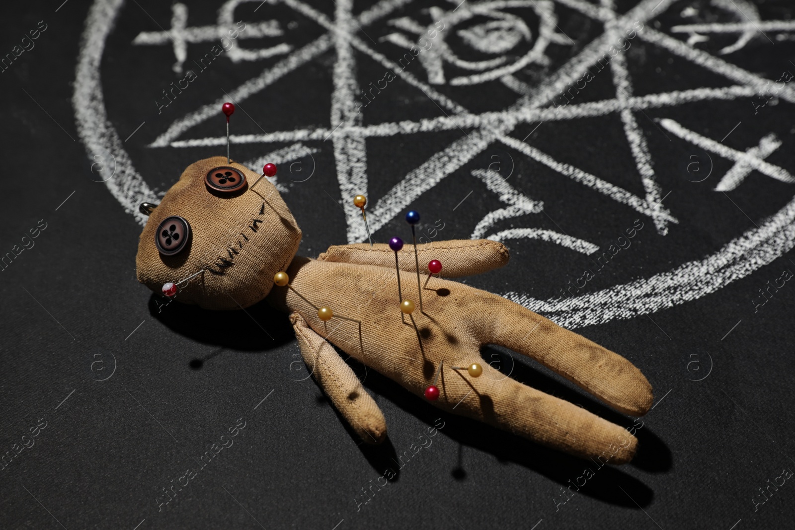 Photo of Voodoo doll near ritual circle drawn on black table