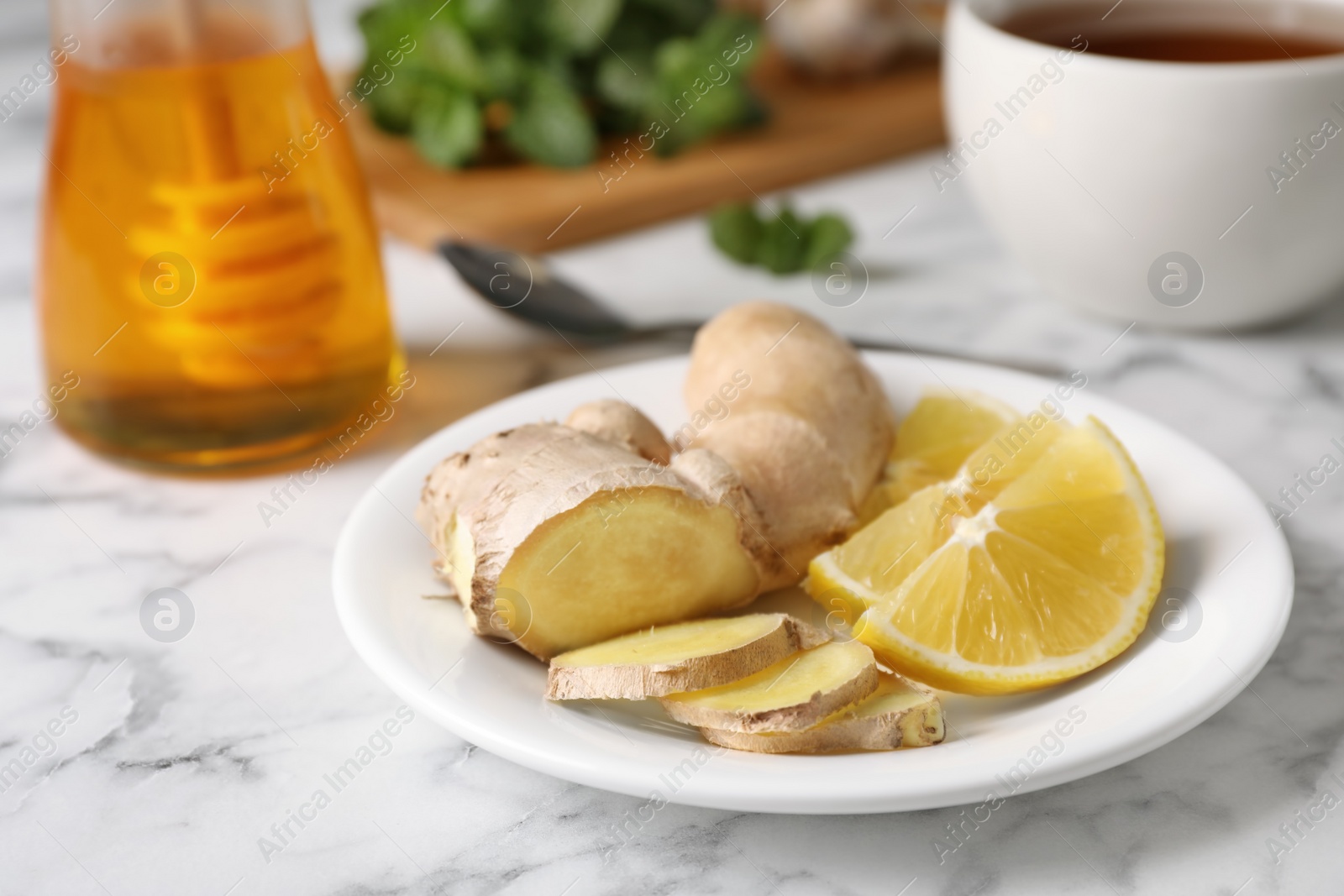 Photo of Plate with lemon and ginger on marble table, space for text. Cough remedies