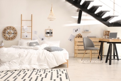 Photo of Elegant interior of bedroom with workplace under stairs