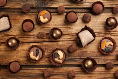 Different delicious chocolate candies on wooden table, flat lay