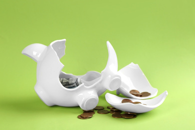 Broken piggy bank with money on green background