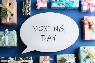 Photo of Speech bubble with phrase BOXING DAY and Christmas decorations on blue background, flat lay