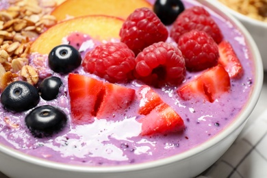 Photo of Delicious acai smoothie with fruits and oatmeal in bowl, closeup