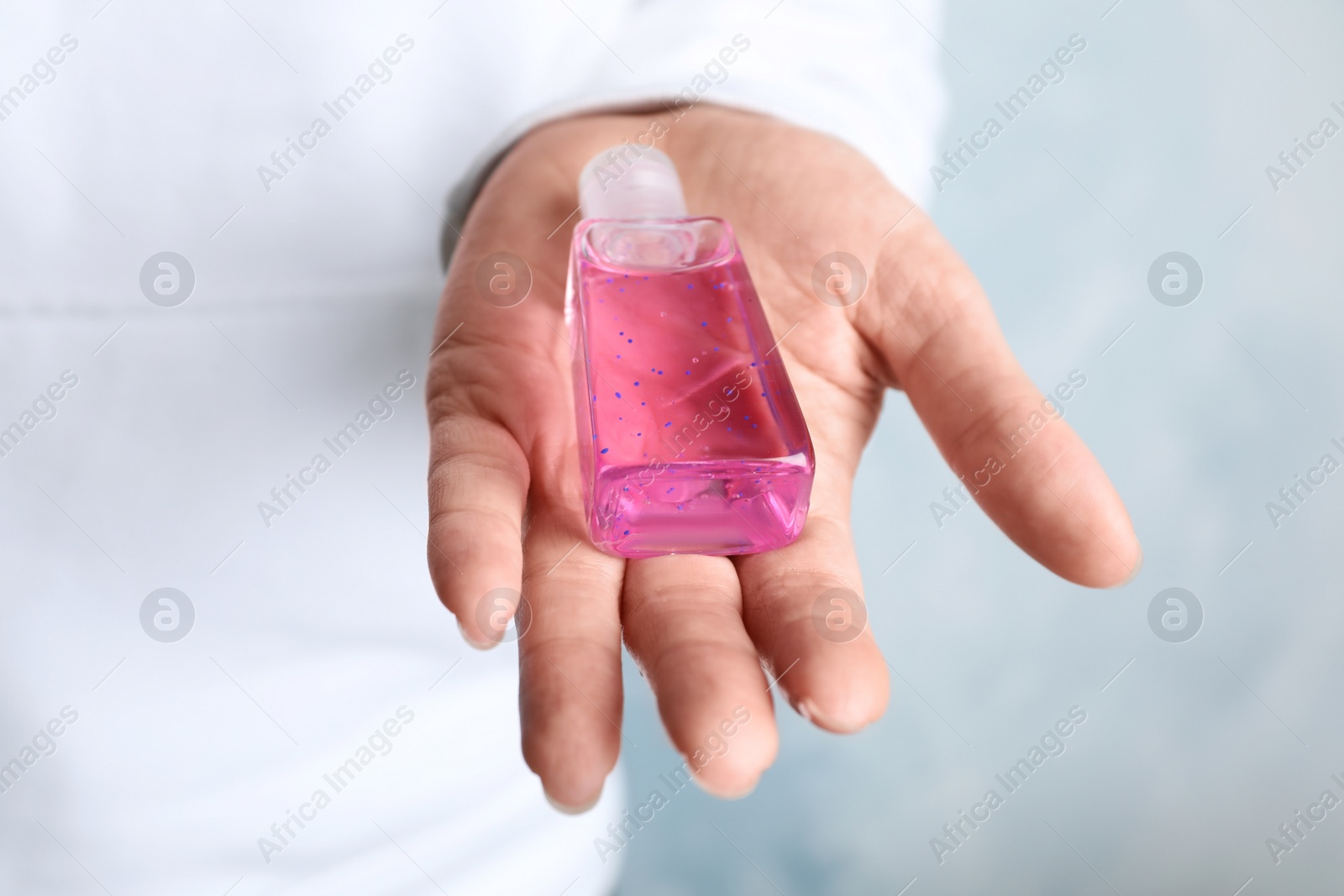 Photo of Woman holding antiseptic gel on light background, closeup
