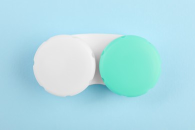 Case with color contact lenses on light blue background, top view