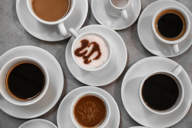 Cups of fresh aromatic coffee on grey background, top view