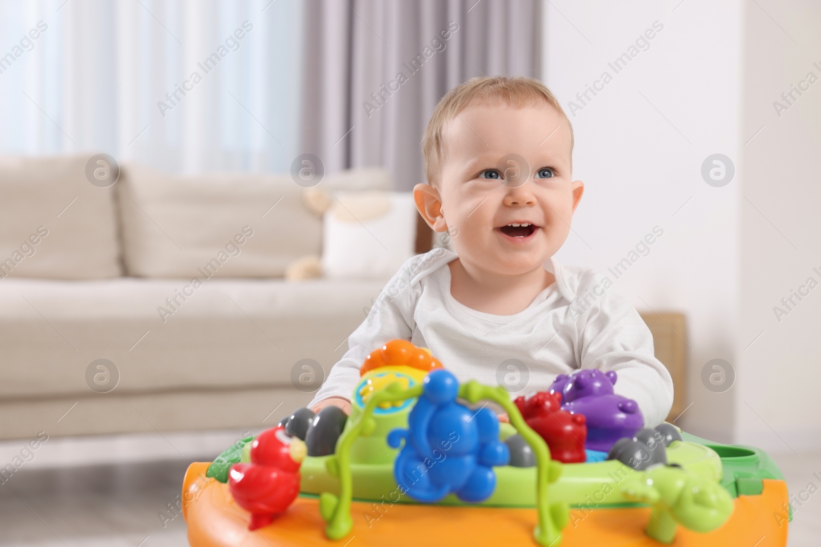 Photo of Happy little boy in baby walker at home, space for text