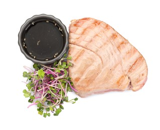 Photo of Delicious tuna steak with sauce and microgreens isolated on white, top view